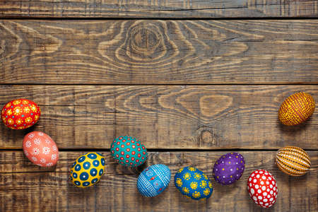 Colorful Easter eggs in a handmade on wooden background with spaceの写真素材