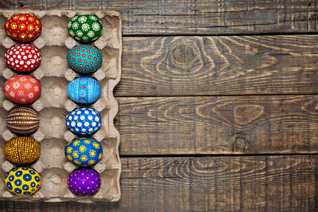 Painted in handmade Easter eggs is a tray on a wooden backgroundの写真素材