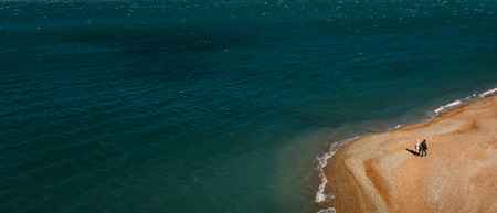 Two people walk along the sea shore, a bird's eye view. Gelendzhik, Russiaの写真素材