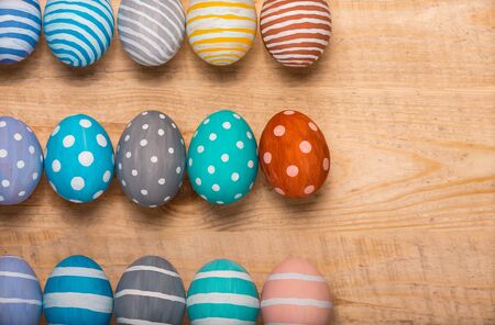 Twelve colorful handmade Easter eggs on a wooden background with space right. Flat lay style.の写真素材