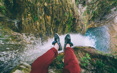 Male Traveler sitting on cliff with waterfall view. Travel Lifestyle adventure vacations conceptの写真素材