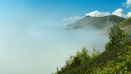 Mountain range against the background of the fog that descended into the valley on sunny day. North Caucasus, Russiaの写真素材