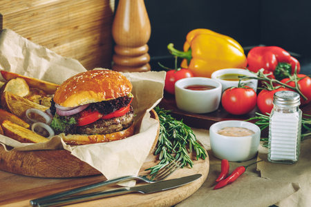 Fresh tasty burgers with french fries and sauce on the wooden and paper table topの写真素材