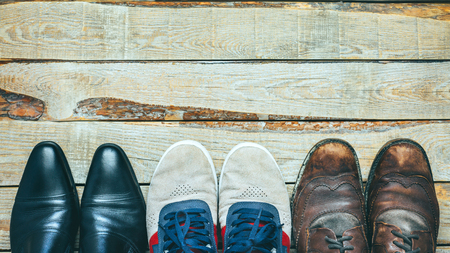 Three pairs of shoes on wooden backgriound: Busines shoes, casual shoes and hiking boots Concept of choosing right footwearの写真素材