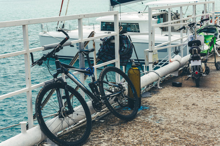 Bike stands on a pier against the background of a sailing yacht on azure sea waterの写真素材