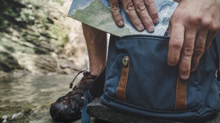 Hiker Man Puts Travel Map In Backpack Exploring Adventure Hiking Conceptの写真素材