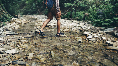 Unrecognizable Tourist With Backpack Crosses Wild River Into ford. Trek Hiking Destination Experience Lifestyle Conceptの写真素材