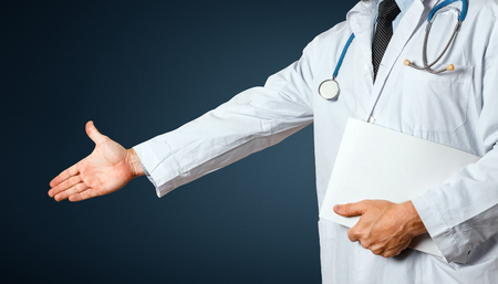 Unrecognizable Man Doctor With Medical Card Holds Out His Hand To Say Hello. Greeting Patient. Healthcare Medicine Conceptの写真素材
