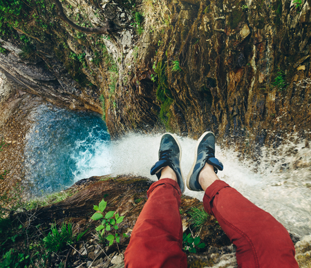 Male Traveler sitting on cliff with waterfall view. Travel Lifestyle adventure vacations conceptの写真素材