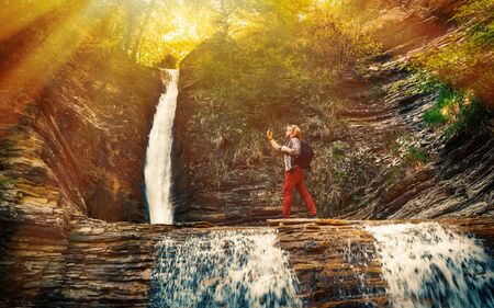 The tourist makes a self-portrait against the backdrop of a landmark waterfallの写真素材