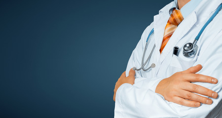 Male Doctor In White Coat With A Stethoscope Crosses His Arms Over His Chest Copy-space. Healthcare Medicine Conceptの写真素材