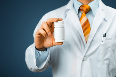 A Male Doctor In White Coat With A Stethoscope On The Shoulder Holding A Bottle Of Pills Between His Fingers. Healthcare Medical Hospital Conceptの写真素材