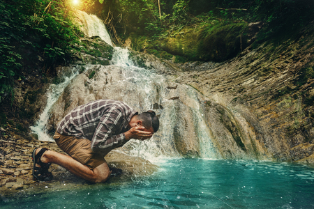 Traveler Explorer Washing His Face In Wild River Destination Experience Lifestyle Conceptの写真素材
