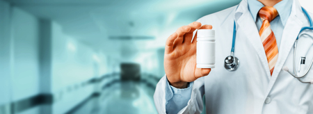 Doctor With Stethoscope On Shoulder Holding a Bottle Of Pills Between His Fingers. Healthcare Medical Hospital Conceptの写真素材