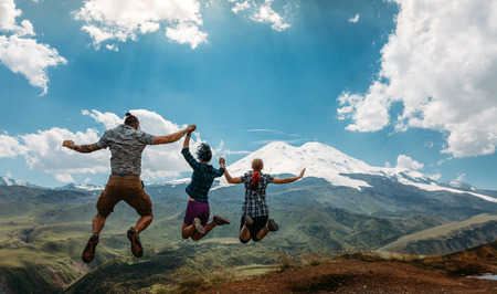 Three Friend Jumping Holding Hands Mountains Elbrus Landscape On Background. Lifestyle Travel Happy...