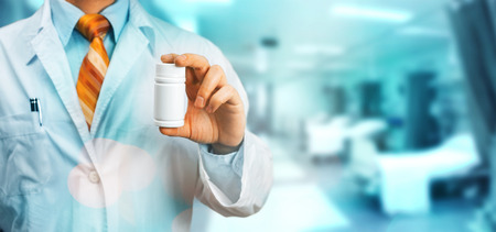 Doctor In White Coat On The Shoulder Holding A Bottle Of Pills Between His Fingers. Healthcare Medical Hospital Conceptの写真素材