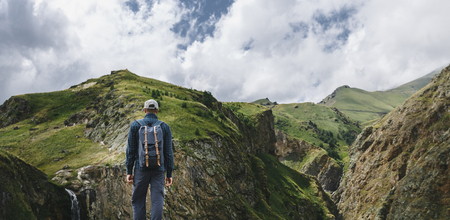 Young Traveler Man Standing On Top Of Cliff In Mountains And Enjoying View Of Nature, Rear Viewの写真素材