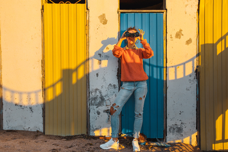 Young Girl Stands Near A Colorful Wall And Looks Through Binocularsの写真素材