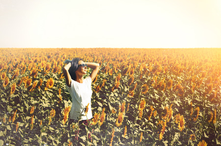 Young Beautiful Girl Standing In Sunflowers And Raising Hands Up. Freedom Lifestyle Journey Conceptの写真素材