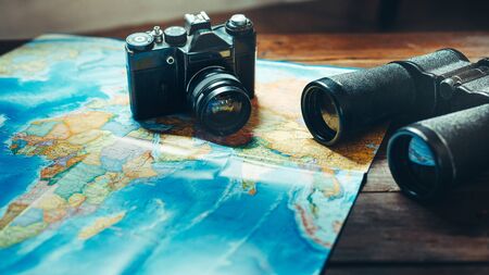 Accessories for travel  Vintage Film Camera, Map And Binoculars On Wooden Table, Front View....