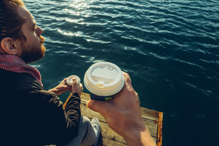 Mens drinking coffee sitting on the pier and enjoying the sea view, Point Of View Shot