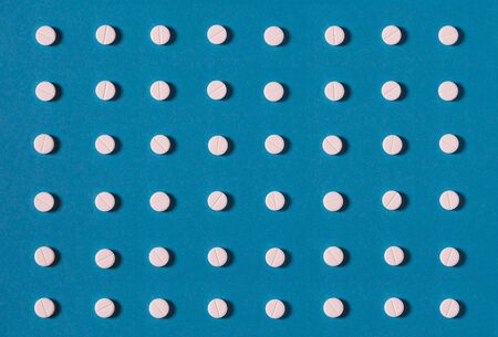 Pattern with white tablets and one colored tablet On Blue Background. Medicine Healthcare Pharmacy Conceptの写真素材