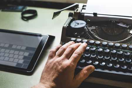 News journalism Concept. Man Hand On Old Typewriter And Digital Tabletの写真素材