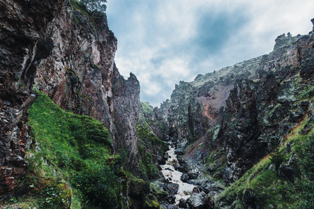 Rough mountain river in the gorge on the background of mountain scenery and clouds. Elbrus, Russiaの写真素材