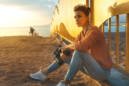 Young beautiful hiking girl sits on the beach and enjoy view of summer nature. Travel Holidays Journey Conceptの写真素材