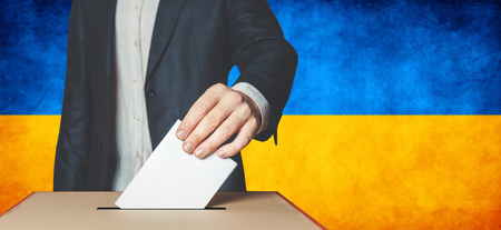 Elections in Ukraine, political struggle. Democracy, freedom and independence concept. Man Voter Putting Ballot In to Voting boxの写真素材