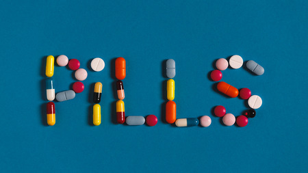 Word Pills Is Lined With Colored Pills And Tablets On A Blue Background, Top Viewの写真素材