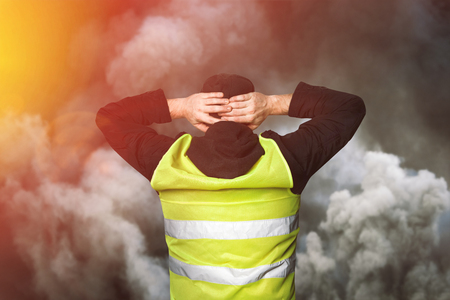 Yellow vests protests. A young man stands with his back and holds his hands on his head as a sign of obedience. The concept of revolution and protest, the struggle for equal rights, the electoral movementの写真素材