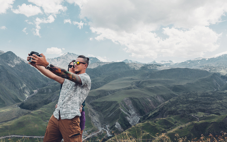 Couple of hikers do selfie on a camera against the backdrop of a picturesque summer mountain landscape. Travel adventure conceptの写真素材