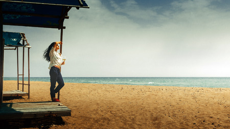 Beautiful Young Girl With a Glass Of Wine Stands On The Beach And Enjoys The Beautiful Scenery. Vacation health happiness conceptの写真素材