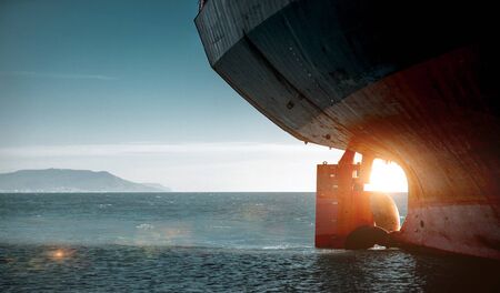 Stern of a cargo ship aground against backdrop of blue sea. World Transport Problems Freight...