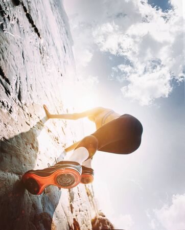 Beautiful Woman Climbing on the High Rock at Blue Sky. Adventure and Extreme Sport Conceptの写真素材