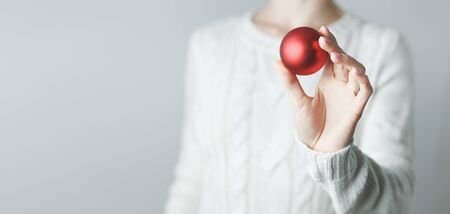 Female Hands Holding A Red Ball Christmas Tree Toy, Close-up With Copy Space. New Year Holidays conceptの写真素材