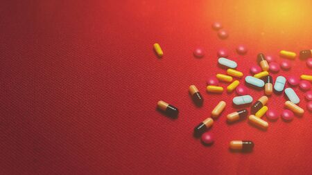 Different Colorful Pills, Tablets And Capsules On Red Backgroundの写真素材