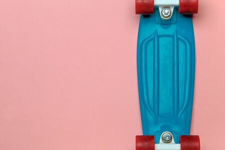 Skateboard cruiser with blue deck and red wheels on pink background, top view with copy-space. Concept of sport lifestyle, culture, leisure, hobby, alternative transportの写真素材