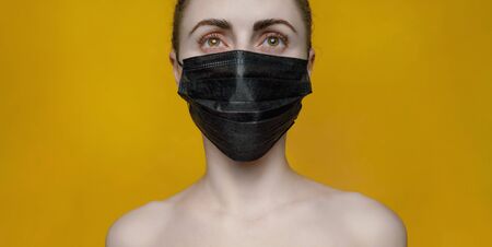 Young woman in protective mask on yellow background banner. Concept Pandemic Epidemic COVID nCoVの写真素材