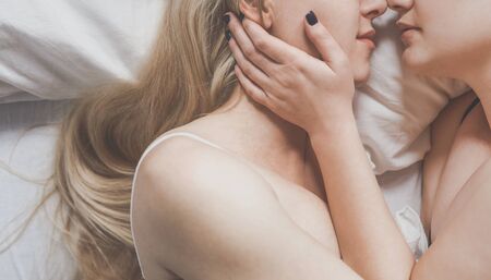 Equal rights and opportunities concept. Lesbian girls gently hug each other lying in bed, top viewの写真素材