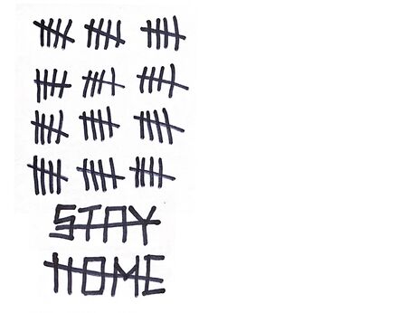 Crossed out Inscription Stay Home and signs tally marks counting the days on a white wall with copy-space. Concept of isolation, quarantine and end of the pandemic coronavirusの写真素材