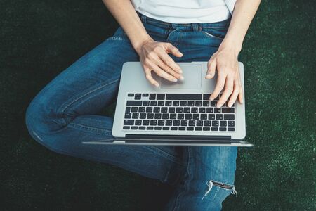Receive news during quarantine lockdown concept. Visual digital detox. Unrecognizable Girl In Casual Clothes Sitting On The Floor With Laptop.の写真素材
