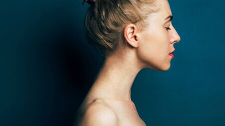 Portrait Of Young Attractive Woman In Profile On Blue Backgroundの写真素材