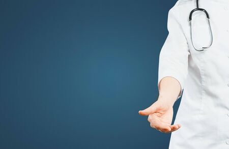 Unrecognizable Friendly Female Doctor Reaches Out To Patient On Blue Background With Copy-spaceの写真素材