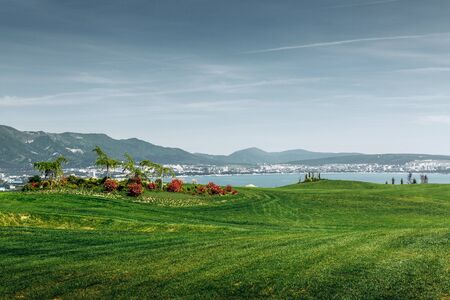 Green Golf Course With Mountains And Seaの写真素材