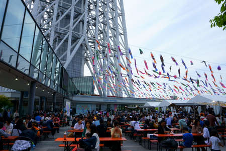 Tokyo / Japan - May 05, 2019: A part of Tokyo skytree tower building. Many cafe visitors sit at outdoor tables. Koinobori decoration for Boy's Dayのeditorial素材