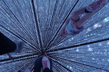Tokyo / Japan - Sept 12 2018: mori digital art museum, Odaiba. electric lights. exhibition by team Lab in the Mori Digital Art Museum. guy in pink shorts. young people take selfies in the mirror floorのeditorial素材