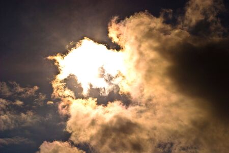 occurring yellow sun behind the clouds on a warm evening の写真素材