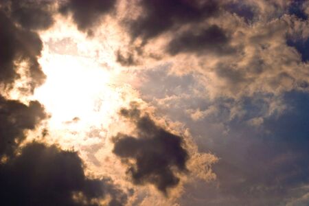 occurring sun behind the blue clouds on a warm eveningの写真素材